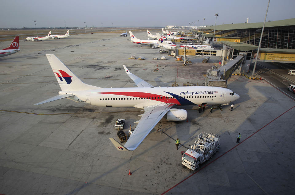 Ground staff work on a Malaysia Airlines plane at Kuala Lumpur International Airport in Sepang, Malaysia, Wednesday, March 12, 2014. The missing Malaysian jetliner may have attempted to turn back before it vanished from radar, but there is no evidence it reached the Strait of Malacca, Malaysia's air force chief said Wednesday, denying reported remarks he said otherwise. The statement suggested continued confusion over where the Boeing 777 might have ended up, more than four days after it disappeared en route to Beijing from Kuala Lumpur with 239 people on board. (AP Photo/Lai Seng Sin)