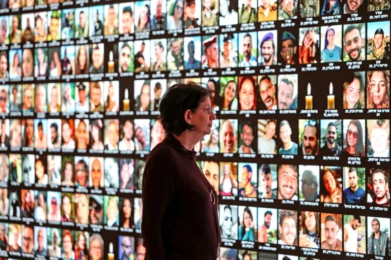Raquel Ukeles of Israel's national library looks at a screen bearing the portraits of Israelis killed during the October 7 attack (AHMAD GHARABLI)