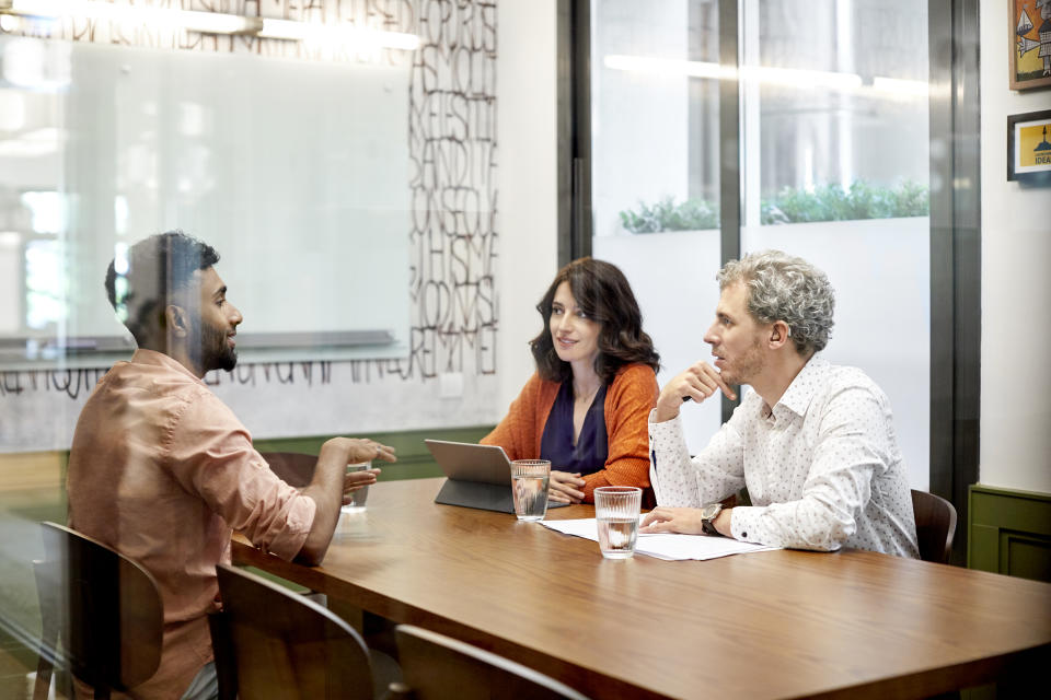 Male and female colleagues discussing in meeting. Business professionals are sitting in board room. They are planning strategy in office.