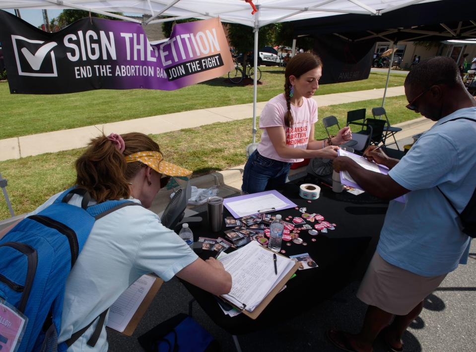 Dina Epstein, center, an OBGYN and physician leader with Arkansans for Limited Government, helps a visitor sign the petition for the Arkansas abortion amendment during the 15th Annual Juneteenth in Da Rock celebration at S. Arch Street in Little Rock, Ark., Saturday, June 15, 2024.