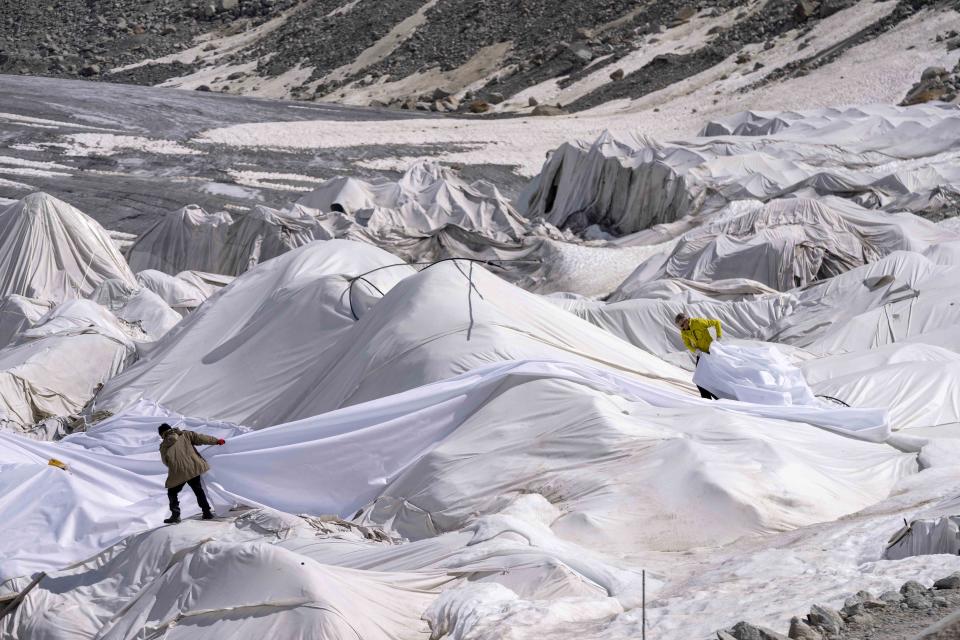 Workers prepare sheets at the Rhone Glacier near Goms, Switzerland, Thursday, June 15, 2023. The sheets are just a small scale solution and Alpine glaciers are still expected to vanish by the end of the century. (AP Photo/Matthias Schrader)