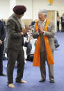 Britain's King Charles III, right, makes the traditional namaste gesture as a traditional shawl for meditation is placed around his shoulders in the Prayer Hall during his visit to the newly built Guru Nanak Gurdwara, in Luton, England, Tuesday, Dec. 6, 2022. (Chris Jackson/Pool Photo via AP)
