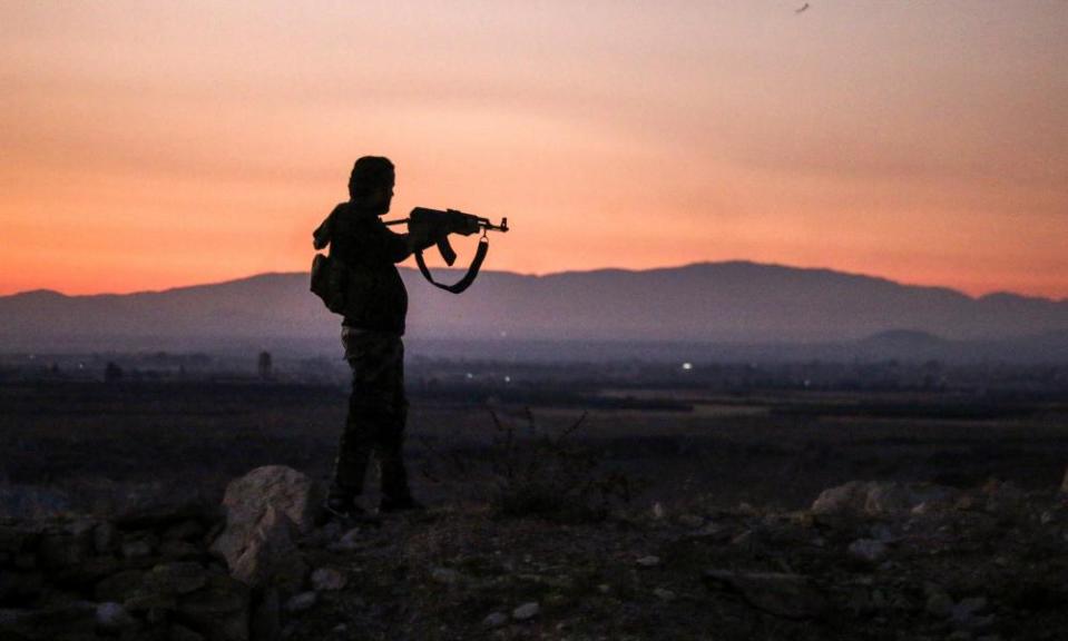 A Syrian rebel fighter aiming his Kalashnikov assault rifle near the frontline of the fight against government forces in Deraa in July 2018.