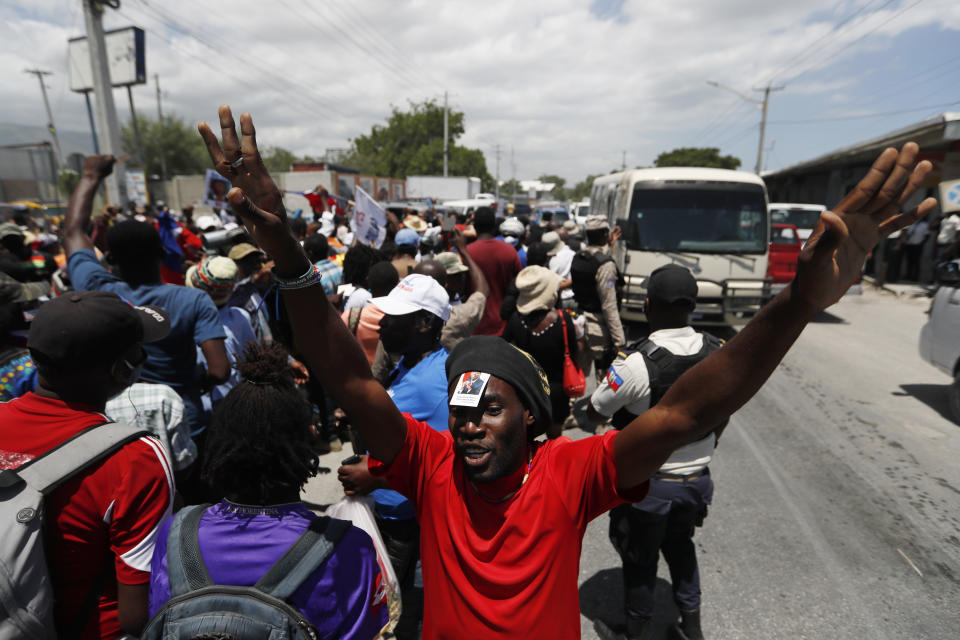 Supporters of former Haitian President Jean-Bertrand Aristide wait near the airport for his expected arrival from Cuba, where he underwent medical treatment, in Port-au-Prince, Haiti, Friday, July 16, 2021. Aristide's return adds a potentially volatile element to an already tense situation in a country facing a power vacuum following the July 7 assassination of President Jovenel Moïse. (AP Photo/Fernando Llano)