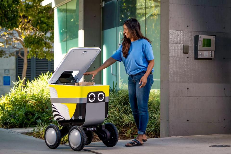 A person accepts a delivery from a Serve Robotics delivery robot.