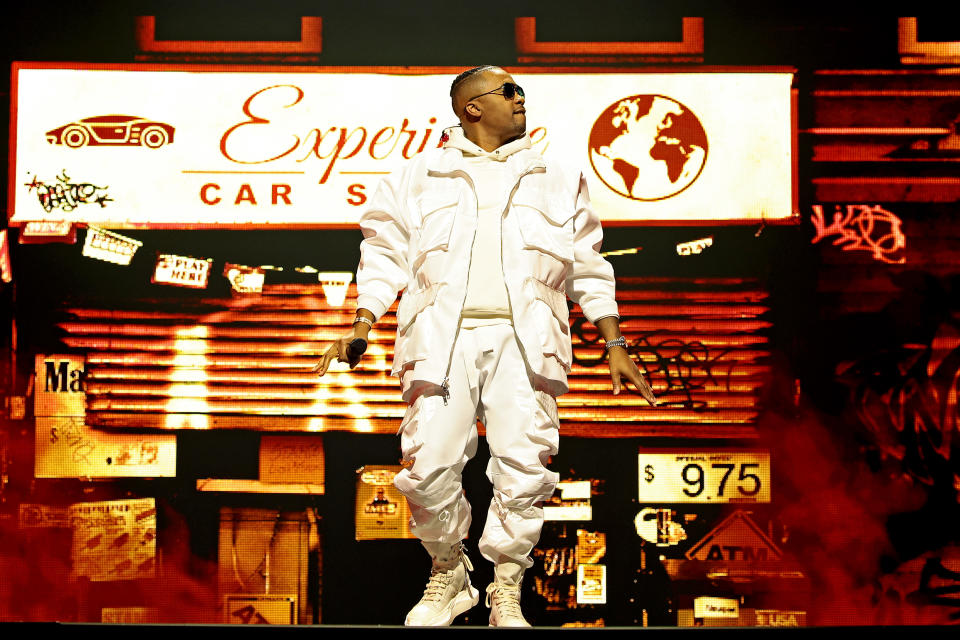 Nas in a white outfit performing on stage