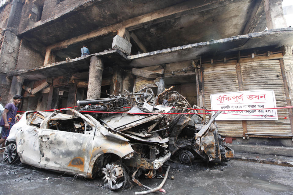 A boy stands by the charred vehicles in Dhaka, Bangladesh, Friday, Feb. 22, 2019. Police on Friday were seeking up to a dozen suspects in connection with a fire in the oldest part of Bangladesh's capital that killed scores of people. (AP Photo/Mahmud Hossain Opu )