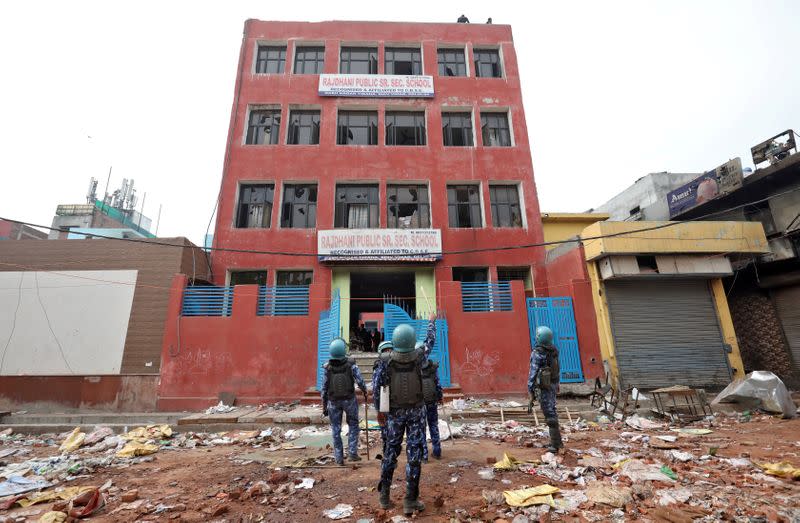 Security forces stand outside a school building that was attacked by a mob in a riot affected area following clashes between people demonstrating for and against a new citizenship law in New Delhi
