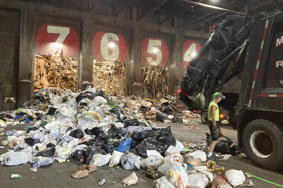 A worker unloads a garbage truck at ecomaine, Tuesday, June 22, 2021, in Portland, Maine. Waste-to-energy converters like ecomaine are seeing an uptick in the amount of trash they collect to produce power as the coronavirus pandemic winds down in the U.S. These facilities burn garbage to create electricity. Environmentalists and renewable energy advocates are debating whether creating more energy by burning the excess waste is a safe idea. (AP Photo/Patrick Whittle)