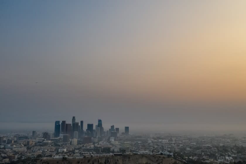 An aerial view of the downtown Los Angeles skyline is obscured by smoke, ash and smog