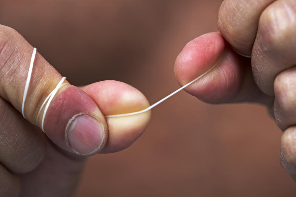 Close-up of a person's fingers pulling a strand of dental floss taut