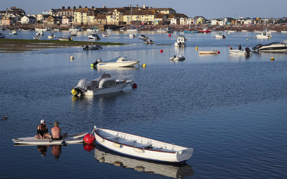 People sit on a paddle board floating in the Teign estuary taken from Shaldon, Devon, England looking across to the holiday resort of Teignmouth, Monday July 19, 2021. (AP Photo/Tony Hicks)