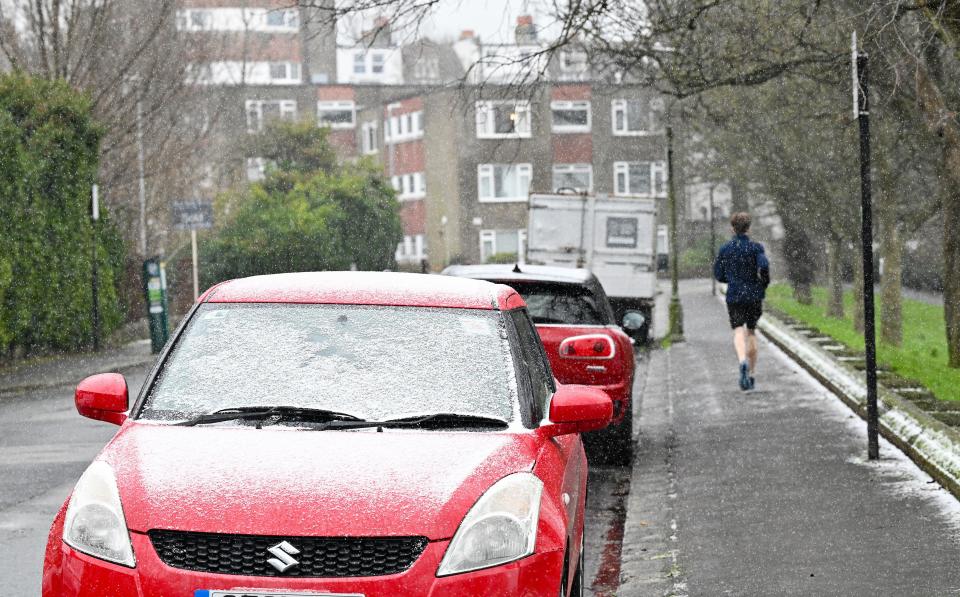 Brighton UK 8th January 2024 - A runner in snow and sleet in Queens Park Brighton as temperatures plummet throughout Britain after the recent wet weather and flooding : Credit Simon Dack / Alamy Live News