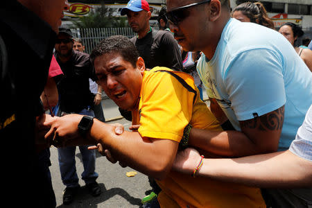 Deputy of the opposition party Justice First (Primero Justicia) Jose Olivares (C) reacts after he was affected by tear gas during a rally against Venezuela's President Nicolas Maduro in Caracas, Venezuela, April 20, 2017. REUTERS/Carlos Garcia Rawlins