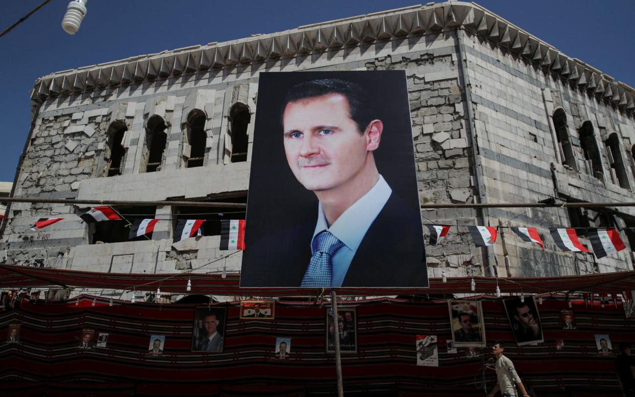 A man walks past a banner depicting Syrian president Bashar al-Assad in Douma, outside Damascus - REUTERS