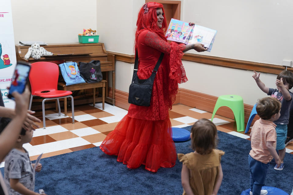 A drag queen who goes by the name Flame reads stories to children and their caretakers during a Drag Story Hour at a public library in New York, Friday, June 17, 2022. (AP Photo/Seth Wenig)