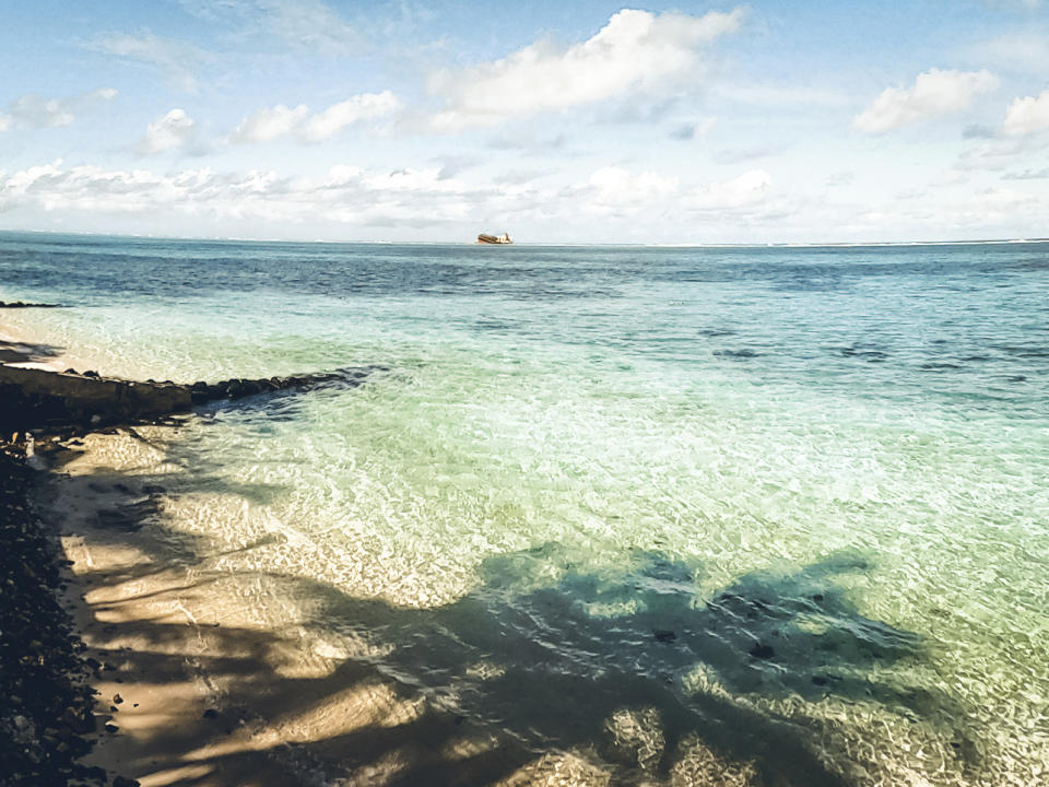 In this photo provided by Grégoire Rouxel is a ship in the distance that ran aground in the ocean earlier this week, Friday, Aug. 7, 2020, in Mauritius. The Indian Ocean island of Mauritius has declared a "state of environmental emergency" after a Japanese-owned ship that ran aground offshore days ago began spilling tons of fuel. Prime Minister Pravind Jugnauth announced the development late Friday, Aug. 7, as satellite images showed a dark slick spreading near environmental areas the government called "very sensitive." (@gregrouxel via AP)