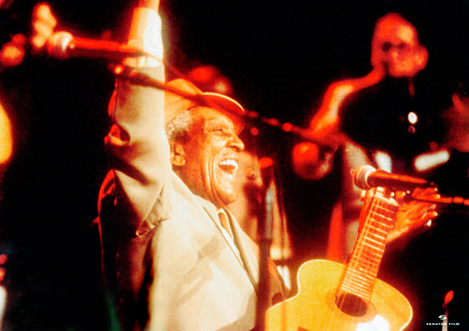 A jubilant man with a guitar performing