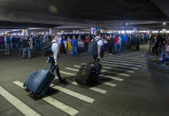 In this Sunday, March 22, 2020 photo, hundreds of people gather to welcome missionaries returning home from the Philippines at the Salt Lake City International Airport. Sen. Mitt Romney and Utah state leaders are criticizing the large gathering of family and friends who went to the airport when people are supposed to be keeping their distance from one another to prevent more spread of the coronavirus. (Rick Egan/The Salt Lake Tribune via AP)