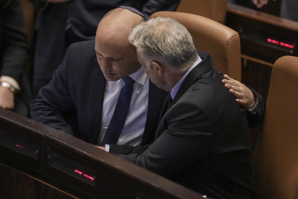 Israeli Prime Minister Naftali Bennett, left, and Foreign Minister Yair Lapid after a vote on a bill to dissolve the parliament, at the Knesset, Israel's parliament, in Jerusalem, Thursday, June 30, 2022. Israel's parliament has voted to dissolve itself, sending the country to the polls for the fifth time in less than four years. (AP Photo/Ariel Schalit)