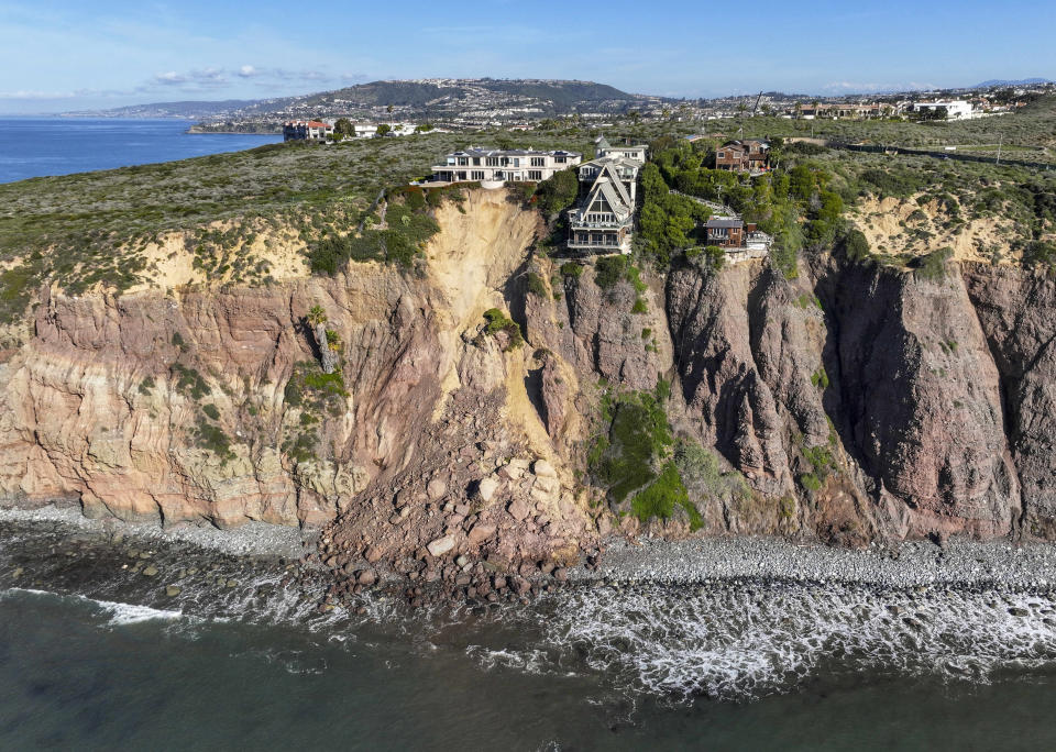 Cliff-top houses along Scenic Drive sit close to a landslide in Dana Point, Calif., on Tuesday, Feb. 13, 2024. The three homes affected by the recent deluge of rain across Orange County are being monitored but don't appear to be in imminent danger, county officials said. (Jeff Gritchen/Orange County Register, SCNG via AP)