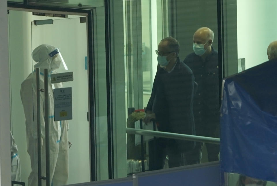 Passengers arriving on the flight from Singapore are processed by staff in protective clothings and directed towards a covered walkway to a separate exit from the airport terminal in Wuhan in central China's Hubei province on Thursday, Jan. 14, 2021. Chinese state media reported that a WHO team arrived in Wuhan, China, on Thursday to research the origins of the coronavirus. (AP Photo/Ng Han Guan)