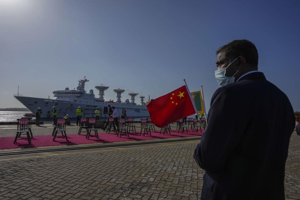 A Sri Lankan port worker holds a Chinese national flag to welcome Chinese research ship Yuan Wang 5 as it arrives in Hambantota International Port in Hambantota, Sri Lanka, Tuesday, Aug. 16, 2022. The ship was originally set to arrive Aug. 11 but the port call was deferred due to apparent security concerns raised by India. (AP Photo/Eranga Jayawardena)