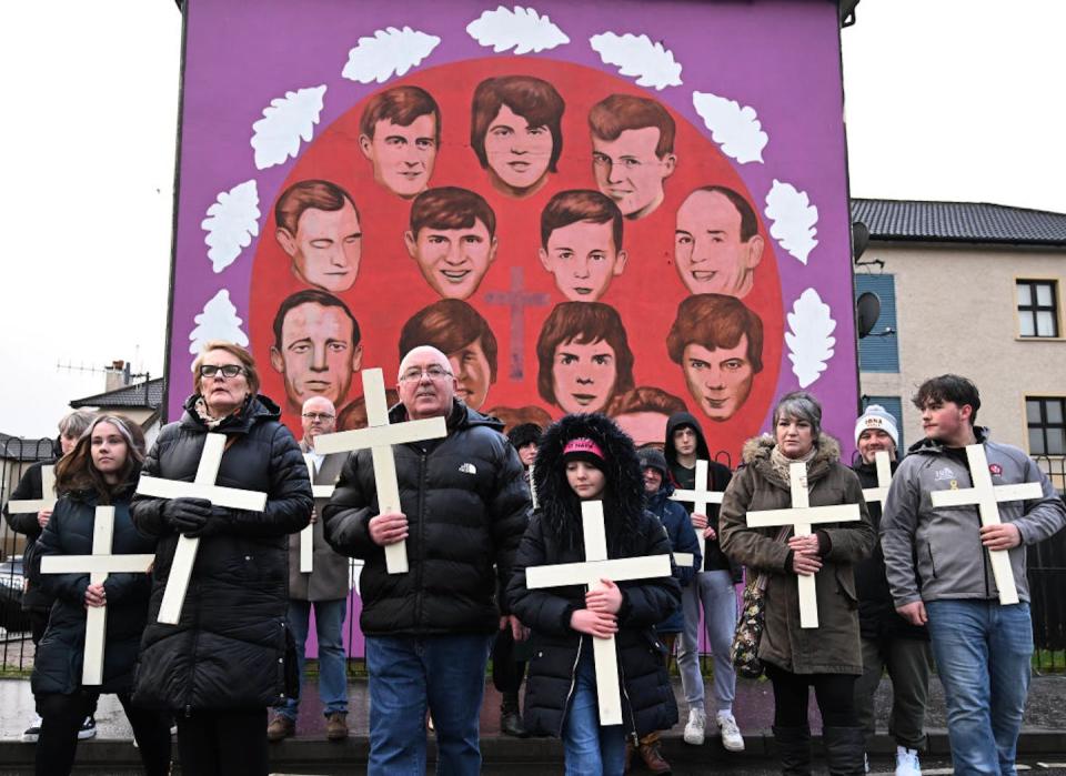 Families of the victims and supporters walk past a mural featuring the 14 victims of Bloody Sunday as they commemorate the 50th anniversary of the massacre, in 2022. <a href="https://www.gettyimages.com/detail/news-photo/families-of-the-victims-and-supporters-walk-past-a-mural-news-photo/1238082451?adppopup=true" rel="nofollow noopener" target="_blank" data-ylk="slk:Charles McQuillan/Getty Images;elm:context_link;itc:0;sec:content-canvas" class="link ">Charles McQuillan/Getty Images</a>