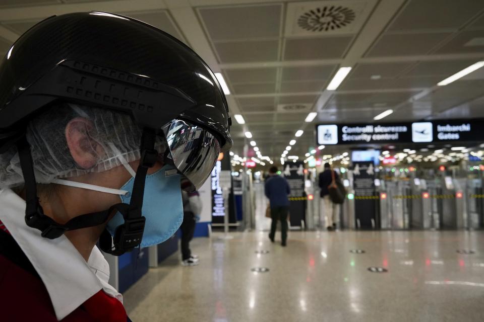 A woman wears a ' smart helmet ' scanner which measures the body temperature of passengers for possible coronavirus symptoms, at Rome's Leonardo da Vinci international airport in Fiumicino, Tuesday, May 12, 2020. (AP Photo/Andrew Medichini)
