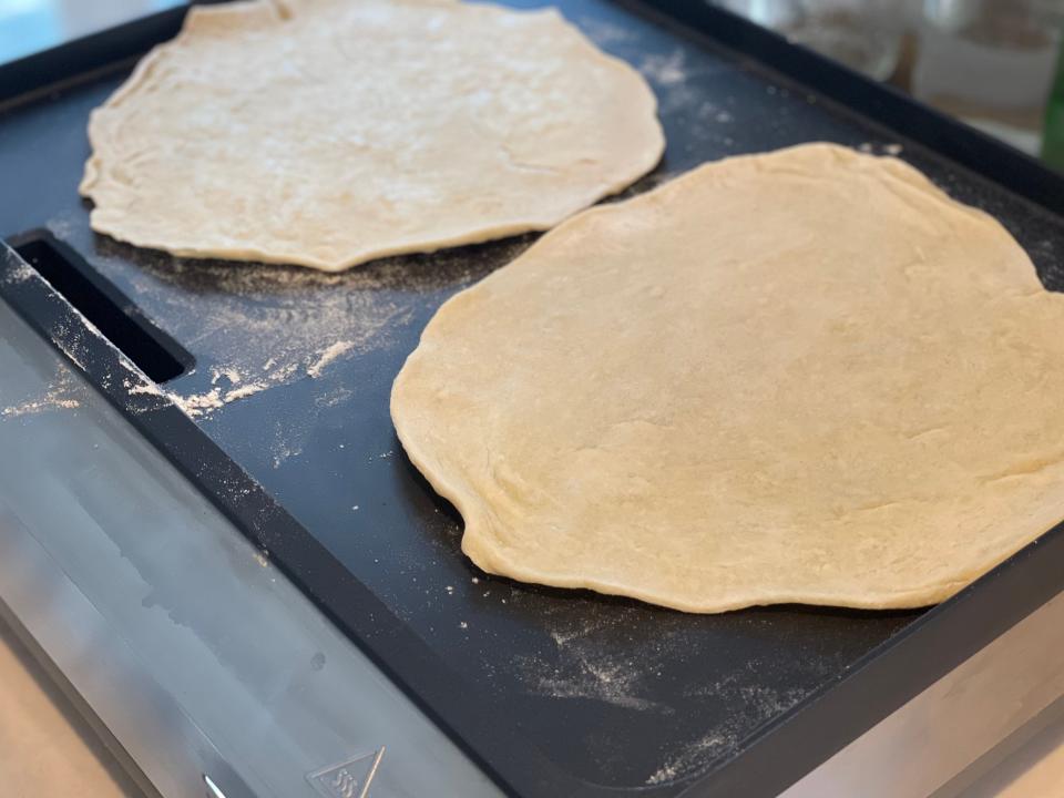 two tortillas cooking on a flat electric griddle