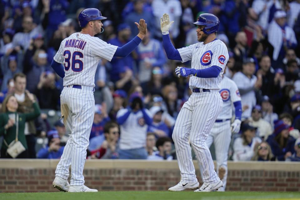 Chicago Cubs first baseman Trey Mancini, left, and Chicago Cubs third baseman Patrick Wisdom both score on a single from Chicago Cubs first baseman Eric Hosmer during the sixth inning of a baseball game Saturday, April 8, 2023, in Chicago. (AP Photo/Erin Hooley)