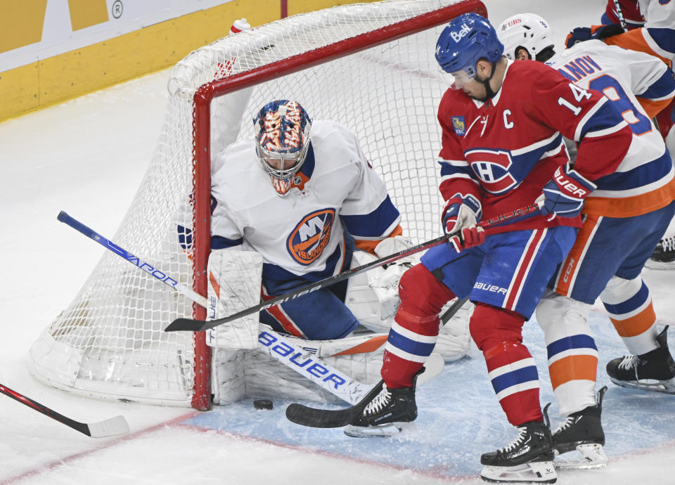 Montreal Canadiens' Nick Suzuki (14) moves in on New York Islanders goaltender Semyon Varlamov during the first period of an NHL hockey match in Montreal, Saturday, Dec. 16, 2023. (Graham Hughes/The Canadian Press via AP)