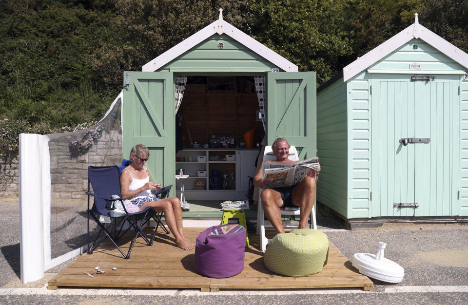 Rob and Sally Underhill sit outside their beach hut on a sunny day, in Bournemouth, England, Wednesday, May 20, 2020. Lockdown restrictions due to the coronavirus outbreak have been relaxed allowing unlimited outdoor exercise and activities such as sunbathing. (Andrew Matthews/PA via AP)