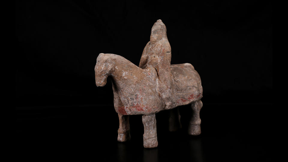 A man on a horse figurine against a black background.