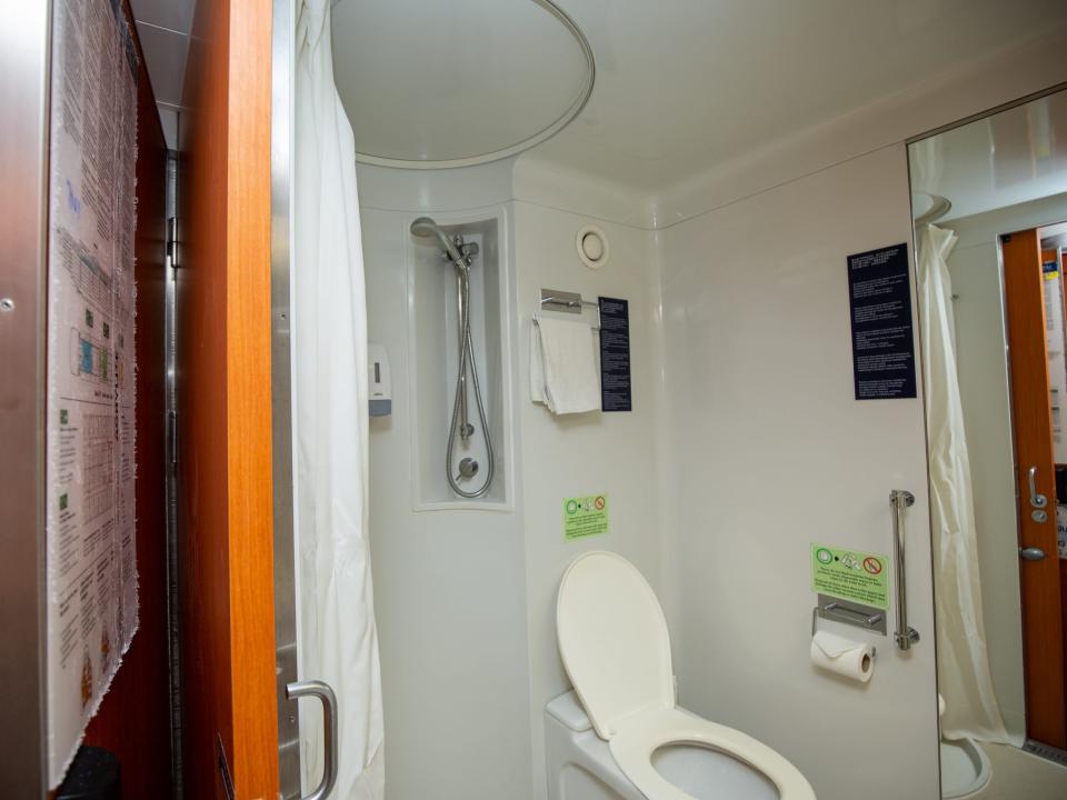 A circular shower with curtain drawn back. The bathroom is next to a wood door.