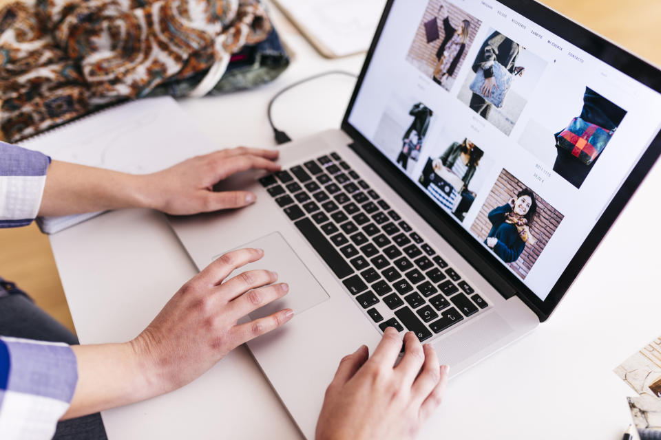 Hands over a laptop show that somebody is browsing through photographs on the laptop's screen