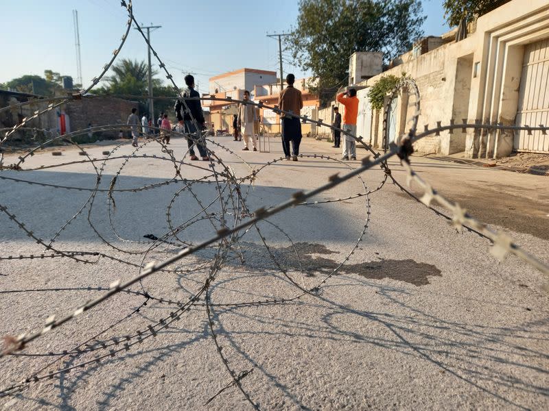 Residents play cricket on a street sealed with barbed wire in Bannu