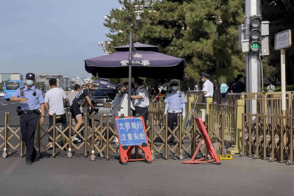 A police officer, left, gestures to a journalist to stop as people on bicycles are ordered to stop for identification check at a checkpoint along a street near Tiananmen Square in Beijing, Sunday, June 4, 2023, during the 34th anniversary of China's bloody 1989 crackdown on pro-democracy protests. (AP Photo/Andy Wong)