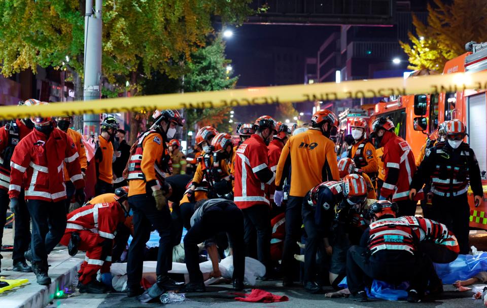 Rescue workers and firefighters work on the scene of a crushing accident in Seoul, South Korea, Saturday, Oct. 29, 2022. South Korean officials say dozens of people were in cardiac arrest after being crushed by a large crowd pushing forward on a narrow street during Halloween festivities in the capital Seoul.