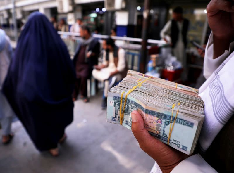 FILE PHOTO: Person holds a bundle of Afghan afghani banknotes at a money exchange market in Kabul