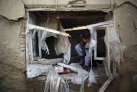 FILE- in this Dec. 11, 2019, photo, a boy inspect his damaged home after after an attack near the Bagram Air Base In Parwan province of Kabul, Afghanistan, A United Nations report says Afghanistan passed a grim milestone with more than 100,000 civilians killed or hurt in the last 10 years since the international body began documenting casualties in a war that has raged for 18 years. (AP Photo/Rahmat Gul, file)