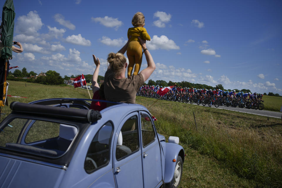 Aficionados al ciclismo observan desde un sedán clásico Citroen 2CV mientras pasan los competidores del Tour de Francia durante la segunda etapa de la carrera ciclista, de más de 202,5 kilómetros (125,8 millas) de Roskilde a Nyborg, Dinamarca, el sábado 2 de julio de 2022. (AP Foto/Daniel Cole)