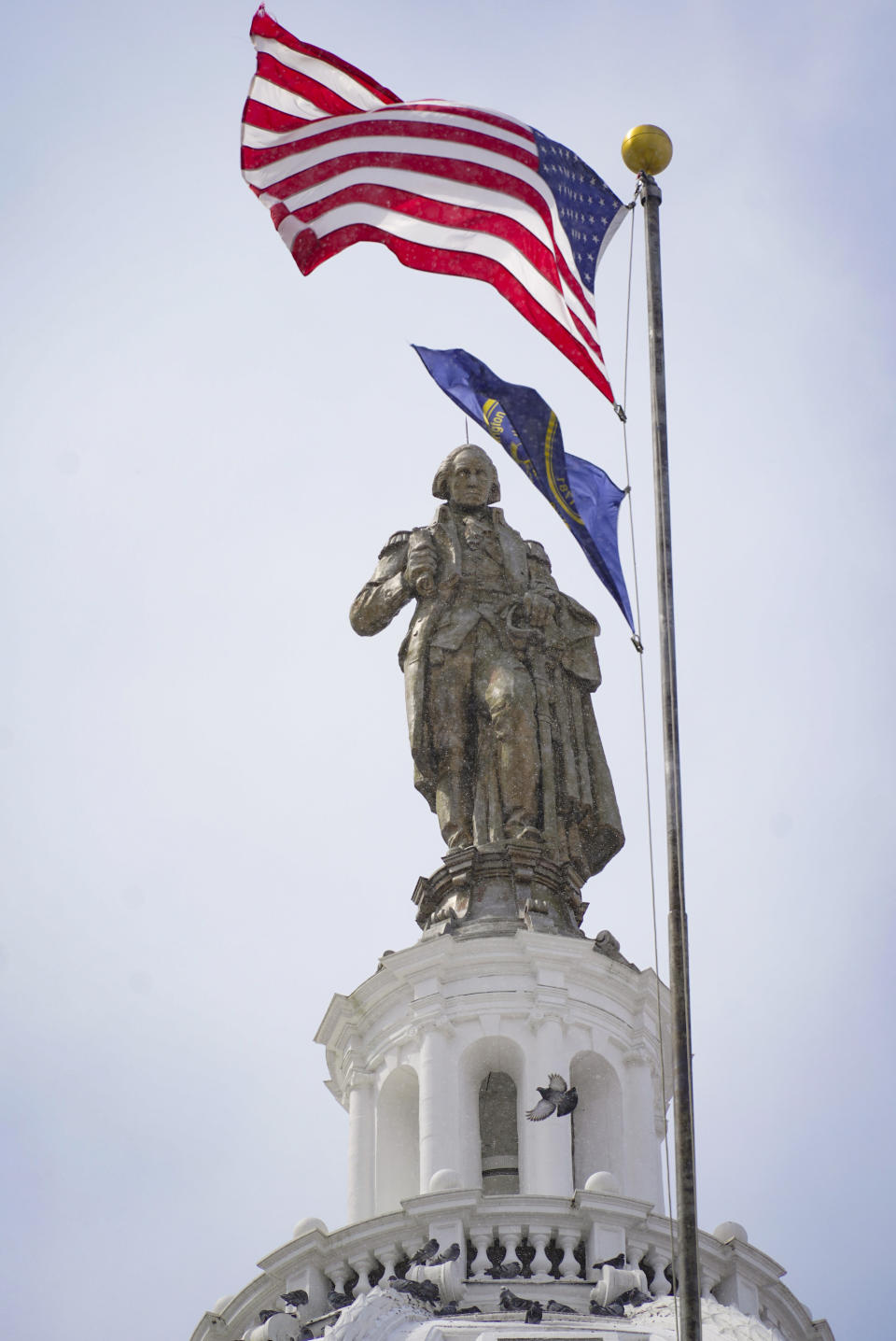 U.S. and county flags fly near the refurbished statue of George Washington and dome of the county courthouse in Washington, Pa., March 28, 2022 Many county improvements have been made possible because the funding made available through shale gas drilling in the county. (AP Photo/Keith Srakocic)