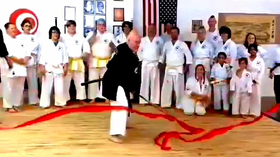 Eric Perkins, co-owner of Okinawan Shorin Ryu Karatedo Kobudo Academy, slices the ribbon to officially open the martial arts school at its new location on Prospect Avenue in Hagerstown.