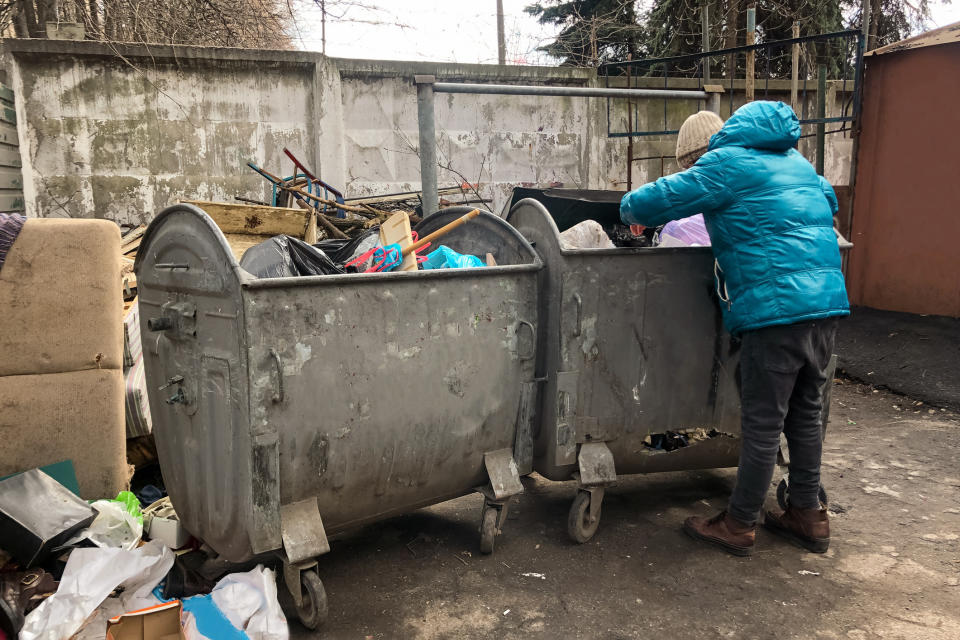 someone looking through a dumpster