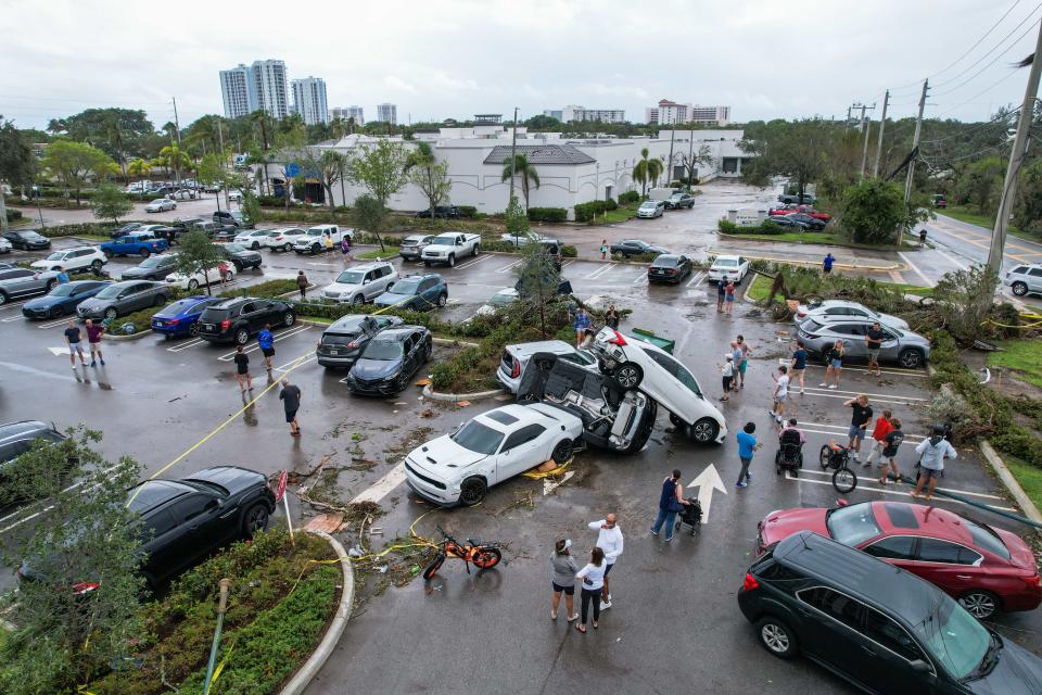 Passers-by stand by a pileup of vehicles at The Point apartment complex in the aftermath of a Saturday evening tornado on Sunday, April 30, 2023, in Palm Beach Gardens, Fla. The National Weather Service confirmed an EF-2 tornado touched down in Palm Beach Gardens Saturday evening.
