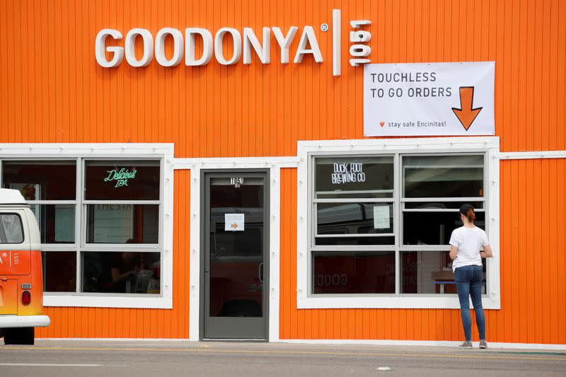 FILE PHOTO: FILE PHOTO: A woman waits for her take-out order at what is usually a sit-down restaurant during the global outbreak of the coronavirus disease (COVID-19) in Encinitas