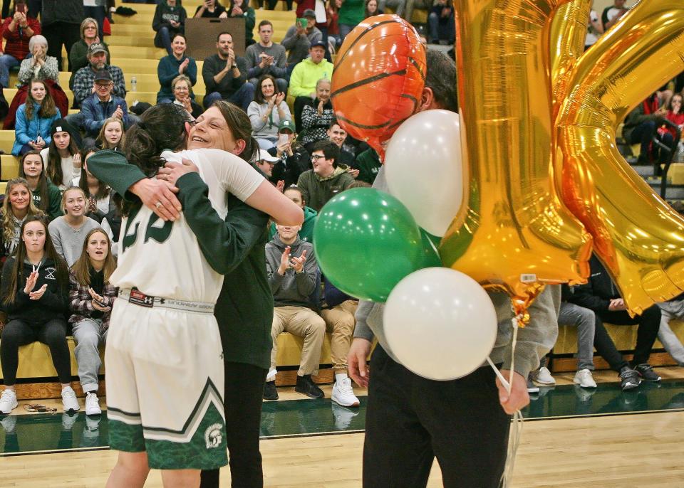 Oakmont's Kylie Lison celebrates scoring her 1,000th career point with a hug from her mother, Rhonda, and balloons from her father, George, during a 2019 game against Quabbin in Ashburnham.