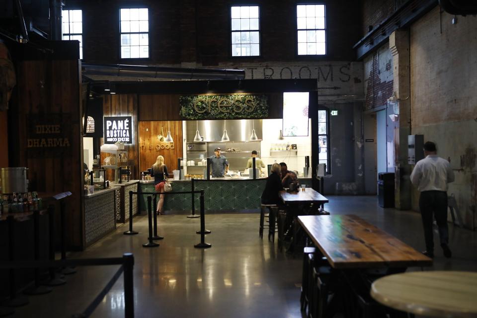 A woman waits for service at Cress, an eatery inside Armature Works in downtown Tampa, Fla., on Monday, March 16, 2020. Tampa's downtown Armature Works issued a statement that it will close at 10 pm until further notice. The decision affects all 20 food, drink and retail businesses at the riverfront entertainment complex. (Octavio Jones/Tampa Bay Times via AP)