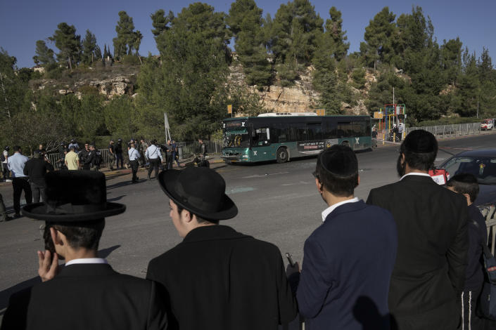 Люди смотрят на место взрыва на автобусной остановке в Иерусалиме.